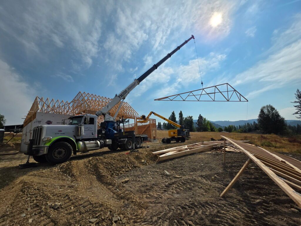 Boom truck setting engineered roof trusses on a new building