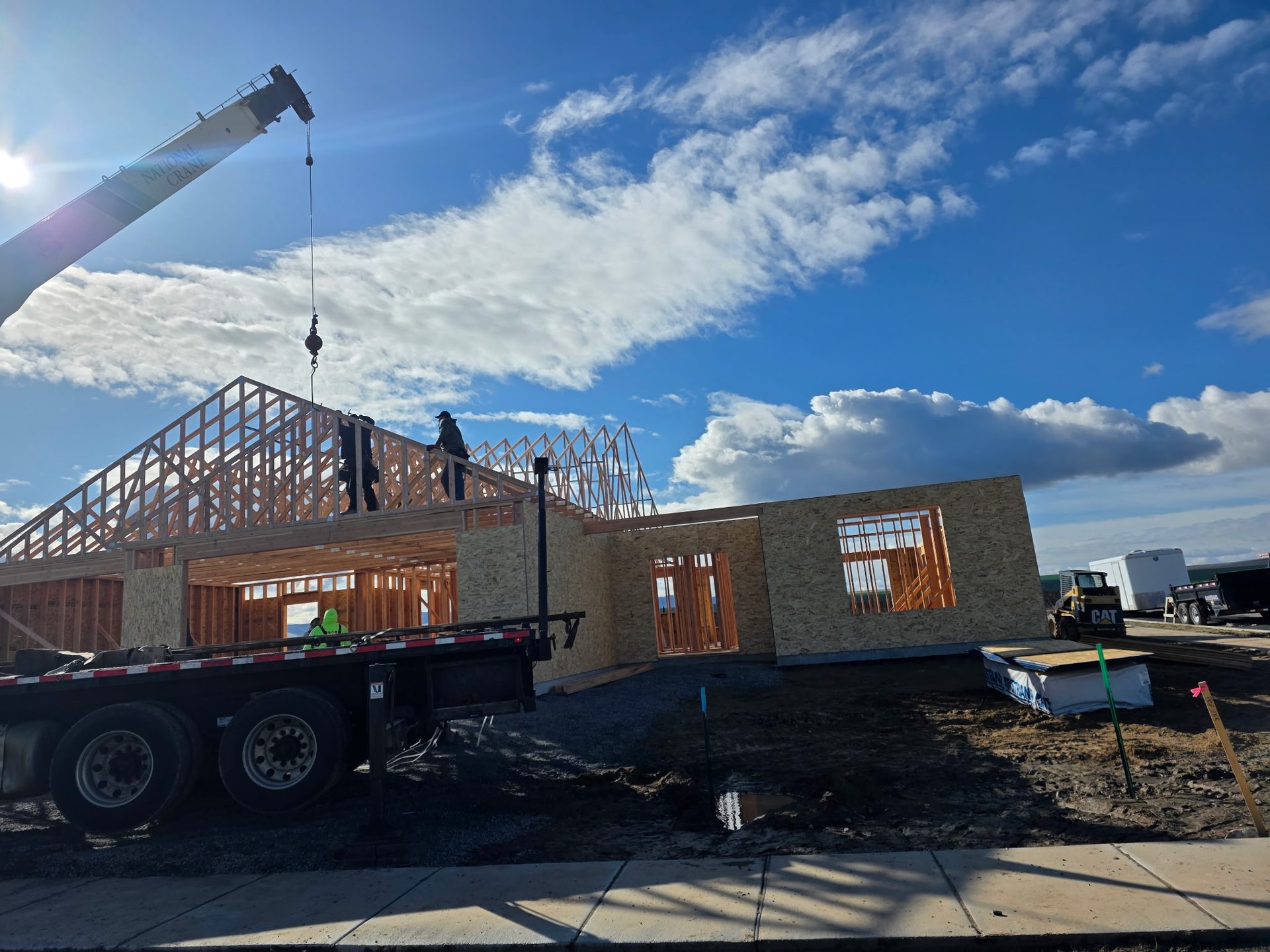 A boom truck setting engineered wood roof trusses on a new building in Lewiston, Idaho